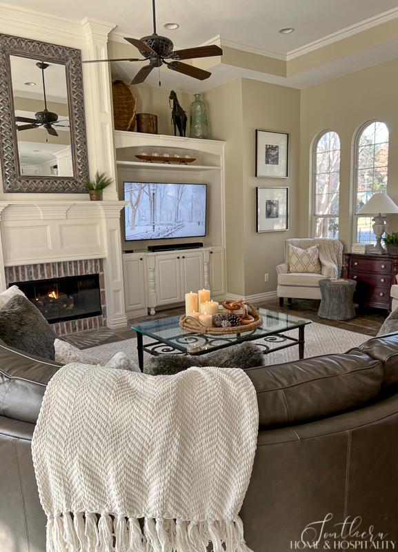 traditional family room with winter decor, fur throw pillows, white throw blanket, winter coffee table vignette, winter art on tv
