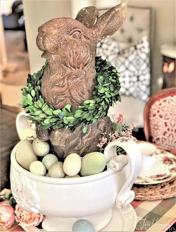Rabbit garden statue in white bowl with Easter eggs and boxwood wreath