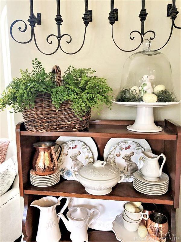 spring decorations layered on white dishes in a hutch