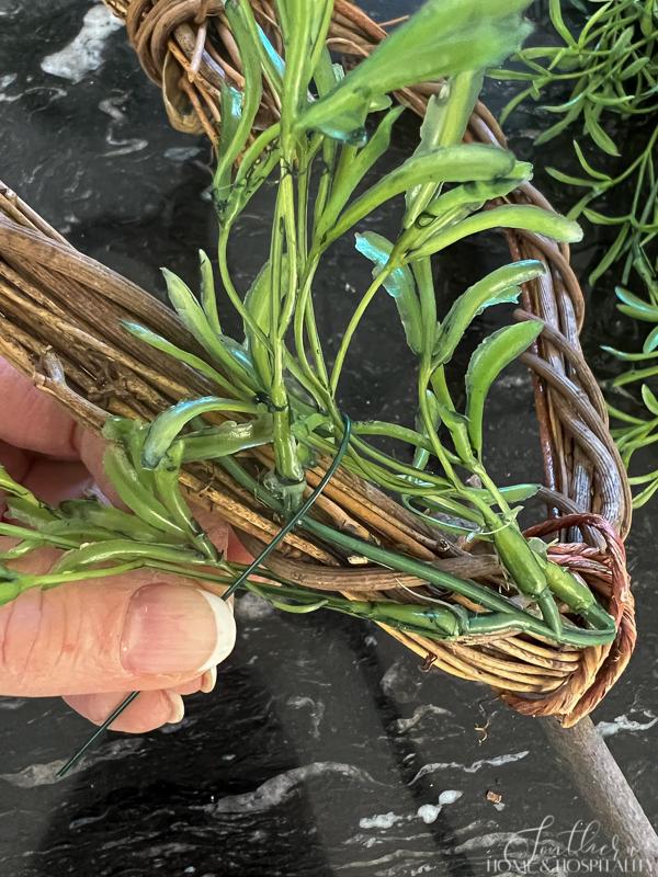 attaching rosemary to wreath form with floral wire