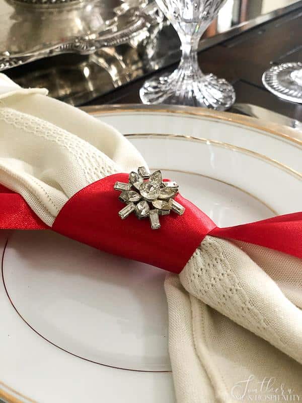 Cloth napkin with red ribbon napkin ring and vintage brooch