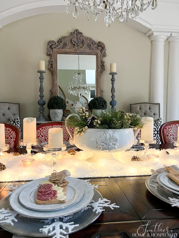 Winter tablescape with snow, candles, fairy lights, and winter greenery, mini charcuterie boards, French sideboard, vintage crystal chandelier