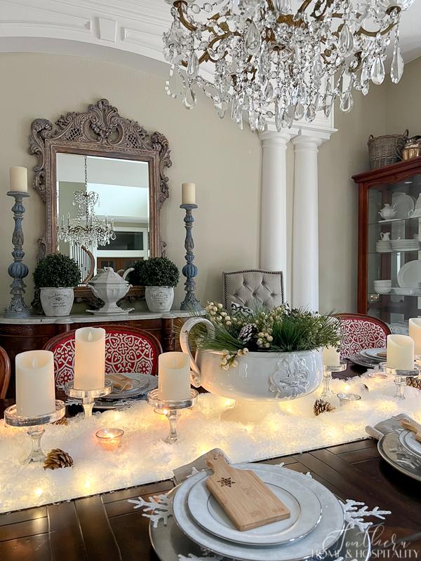Winter tablescape with snow, candles, and winter greenery, mini cutting boards, French sideboard, ironstone, vintage crystal chandelier