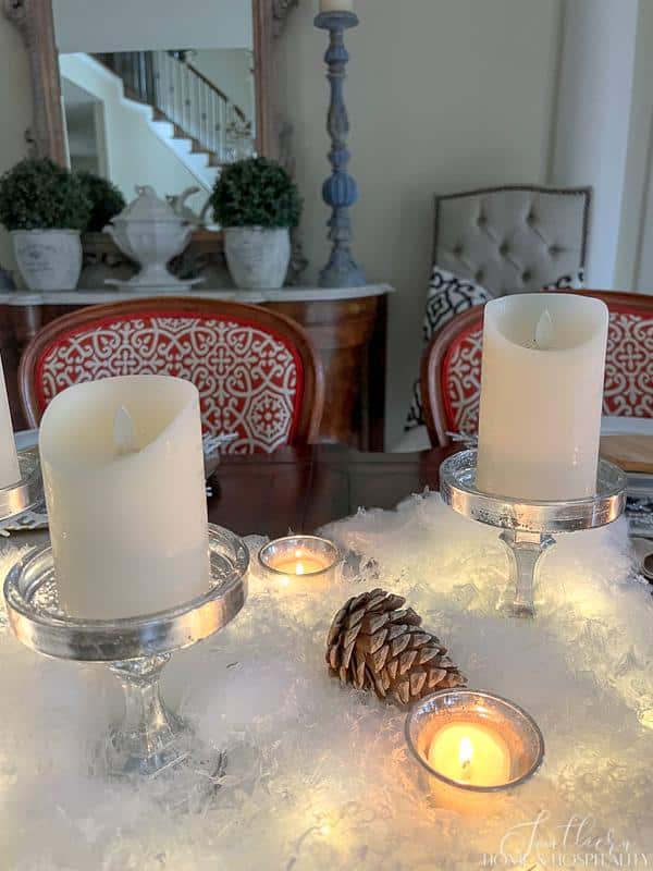 Winter tablescape with snow, candles, and bleached pinecone, French sideboard, ironstone