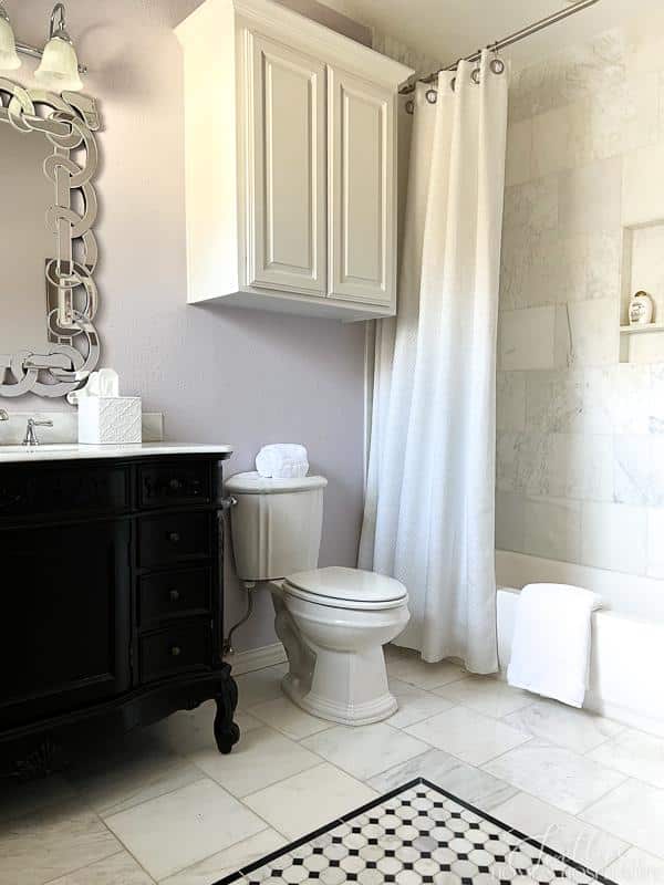 white marble bathroom with lavender walls, black and white mosaic on floor