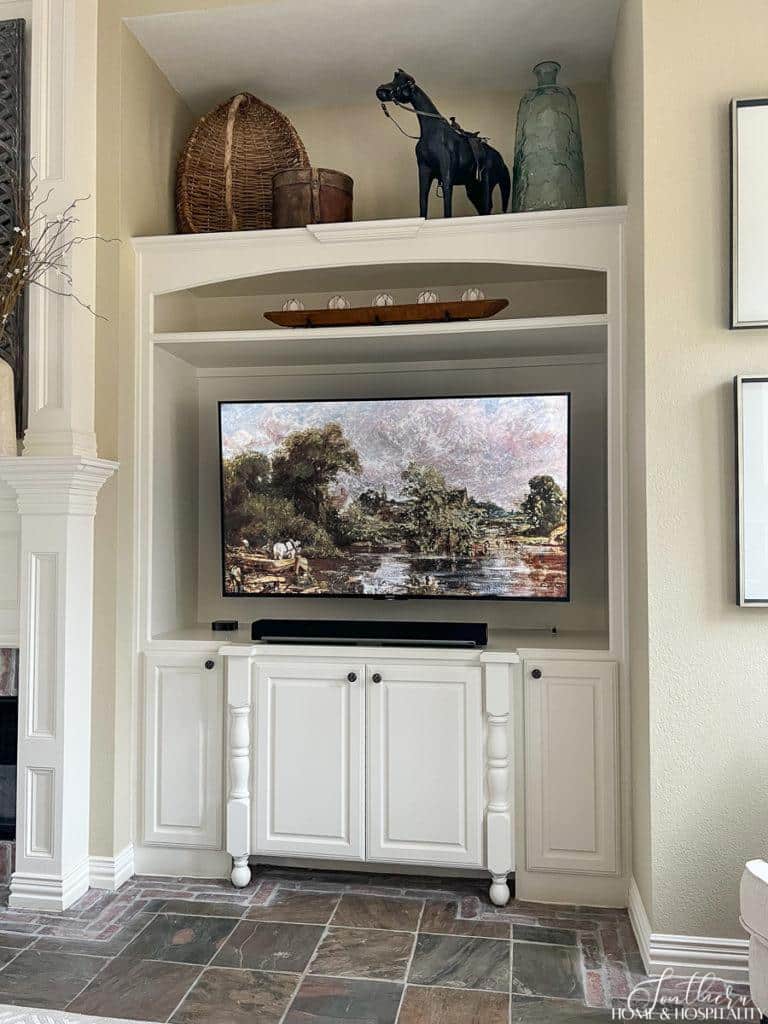 Painted wood built in with flat screen tv displaying vintage oil painting