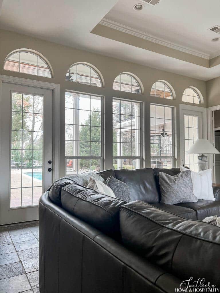 Family room with a wall of arched windows and French doors behind a leather sectional