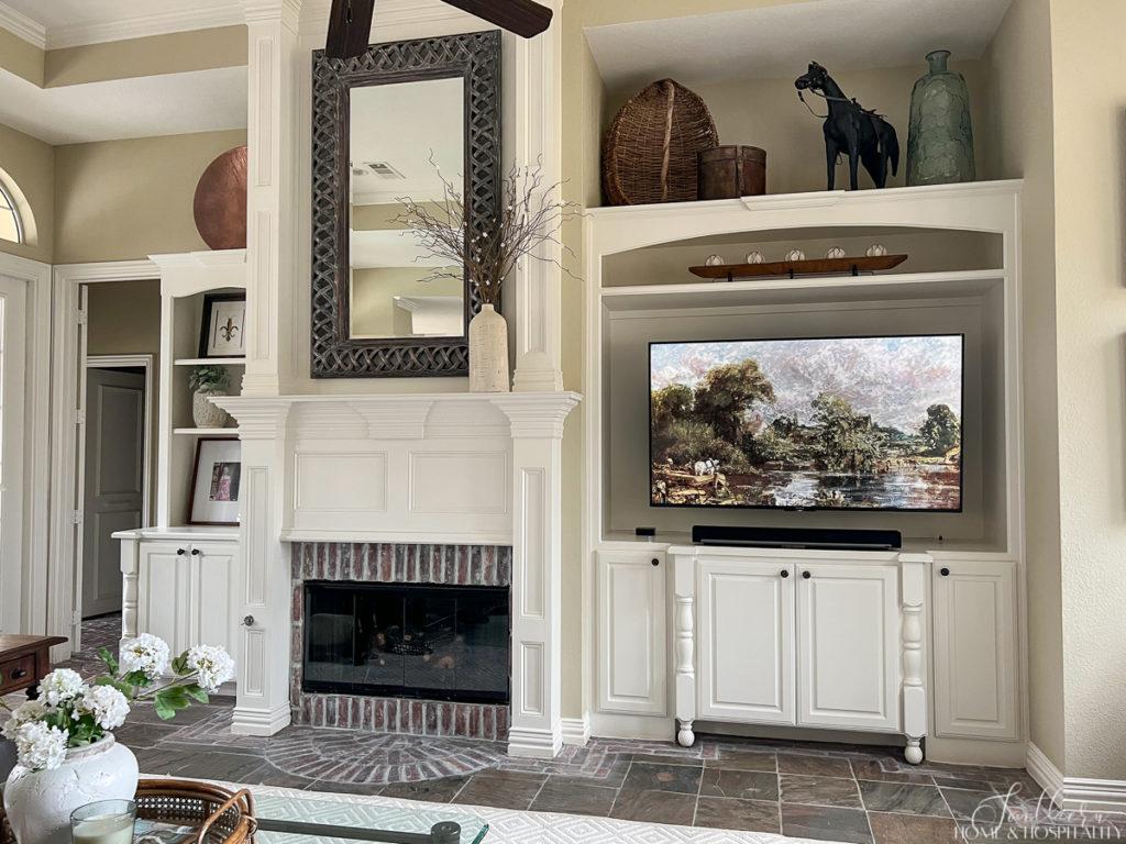 Traditional brick surround fireplace with painted wood mantel and painted wood built ins holding a flat screen tv