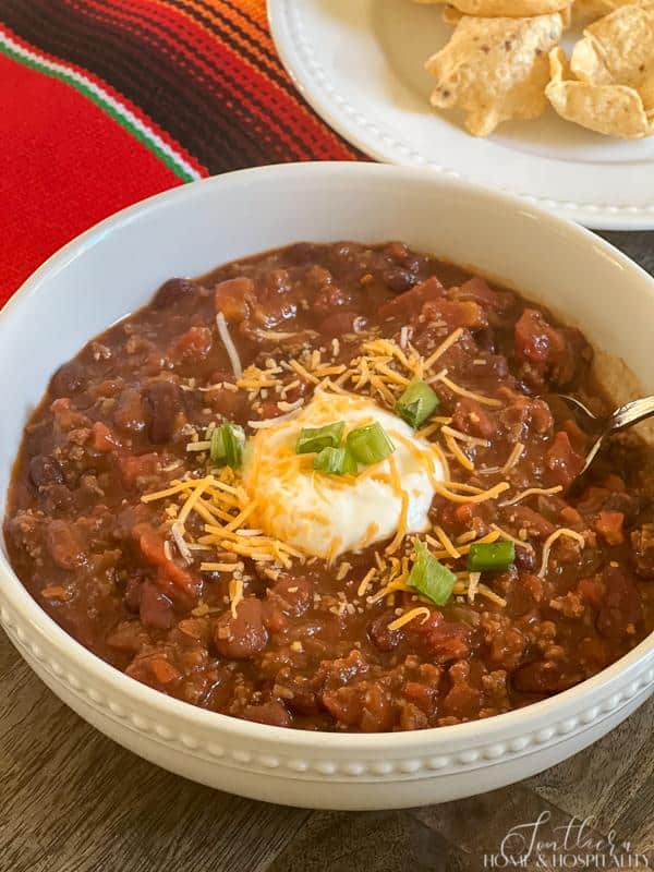 Bowl of taco soup topped with sour cream, shredded cheese, and green onions