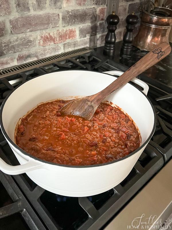 Taco soup cooking on the stovetop in a white enamel cast iron dutch oven