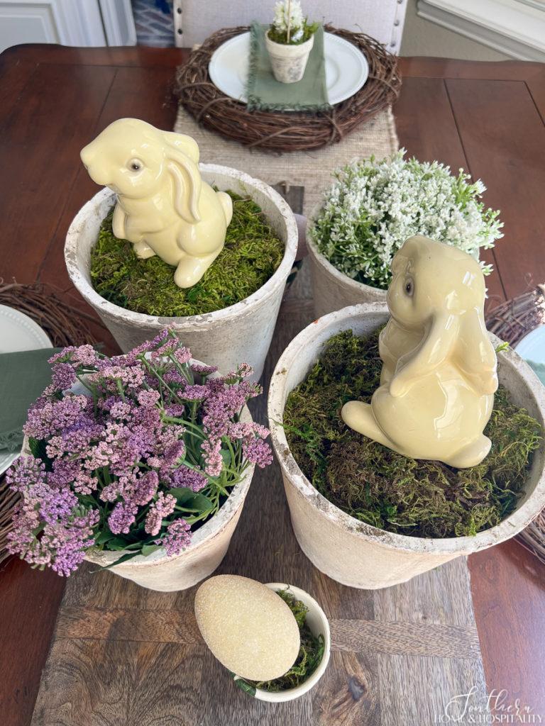 Easter centerpiece with aged garden pots, moss, flowers, and bunnies