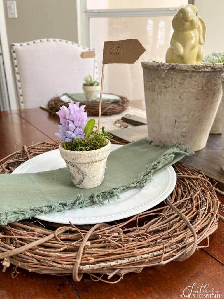 Table setting with grapevine wreath and flower pot on a French farmhouse Easter table