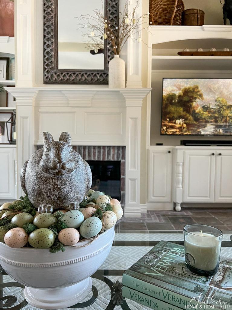 Easter bunny sitting on eggs in a bowl on the coffee table