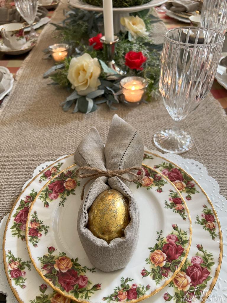 Linen napkin folded like bunny ears with gold egg and Old Country Rose china