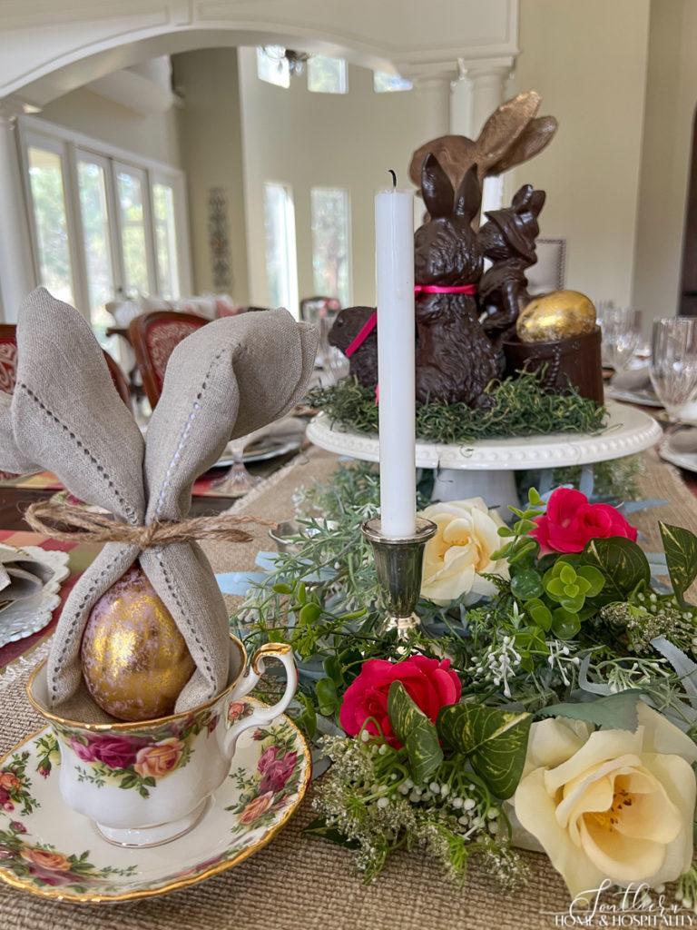 Easter garden table with rose garland and bunny napkin fold in a teacup