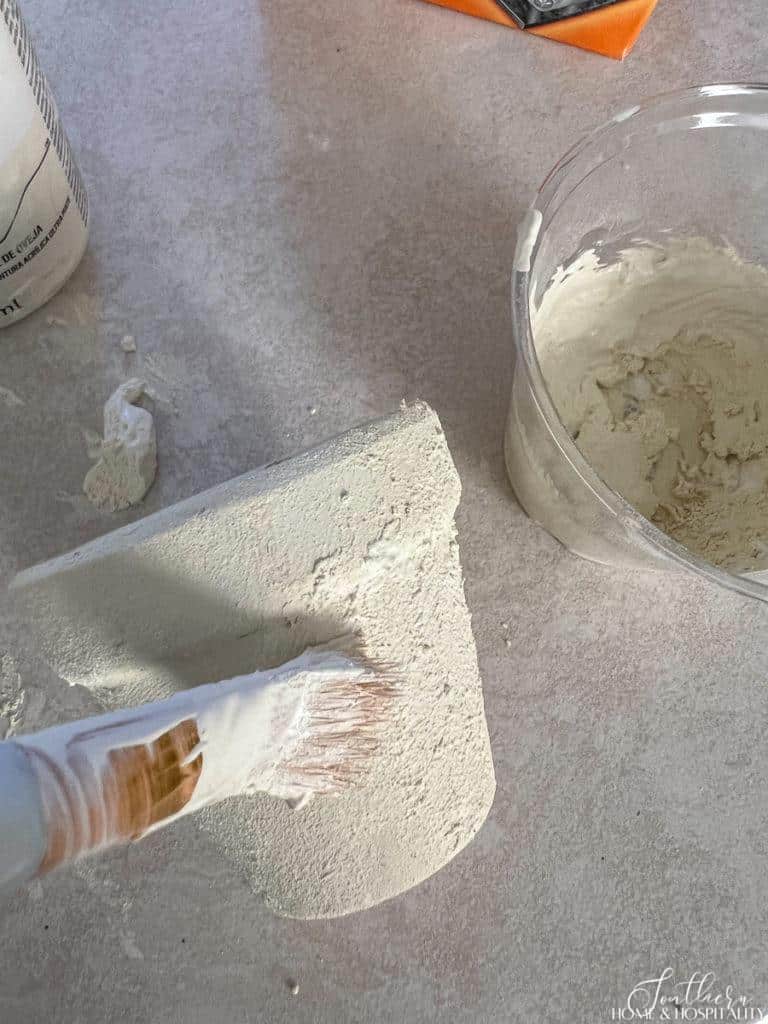 Painting antique white paint and baking soda onto clay flower pot