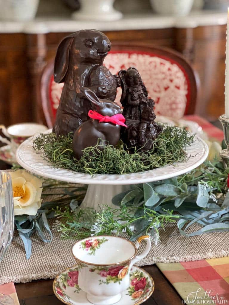 Fake chocolate Easter bunnies displayed on moss on a cake pedestal