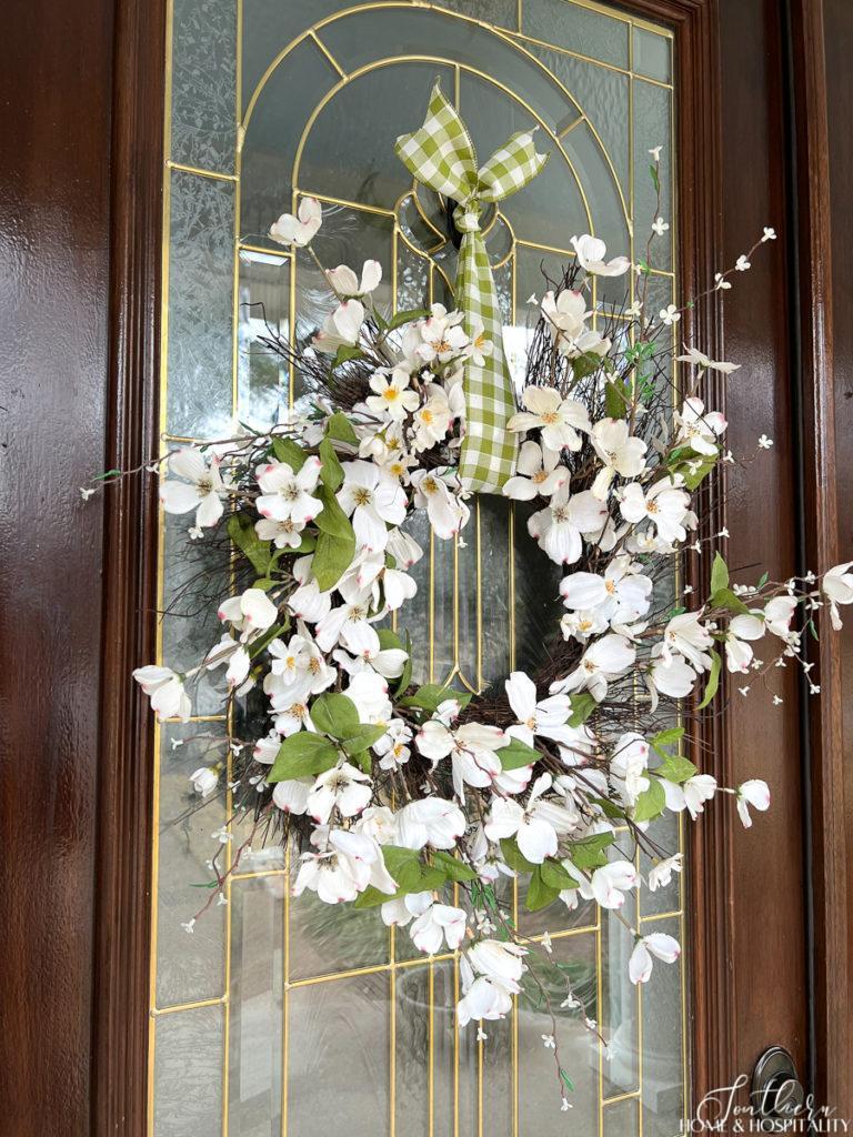 Spring front door wreath with dogwood and white cherry blossoms and green and white gingham ribbon