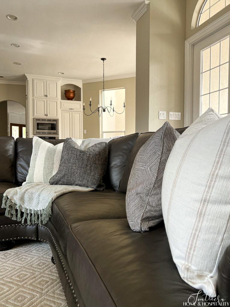 Spring textile pillows in ivory, gray, and green on a leather sectional in the family room