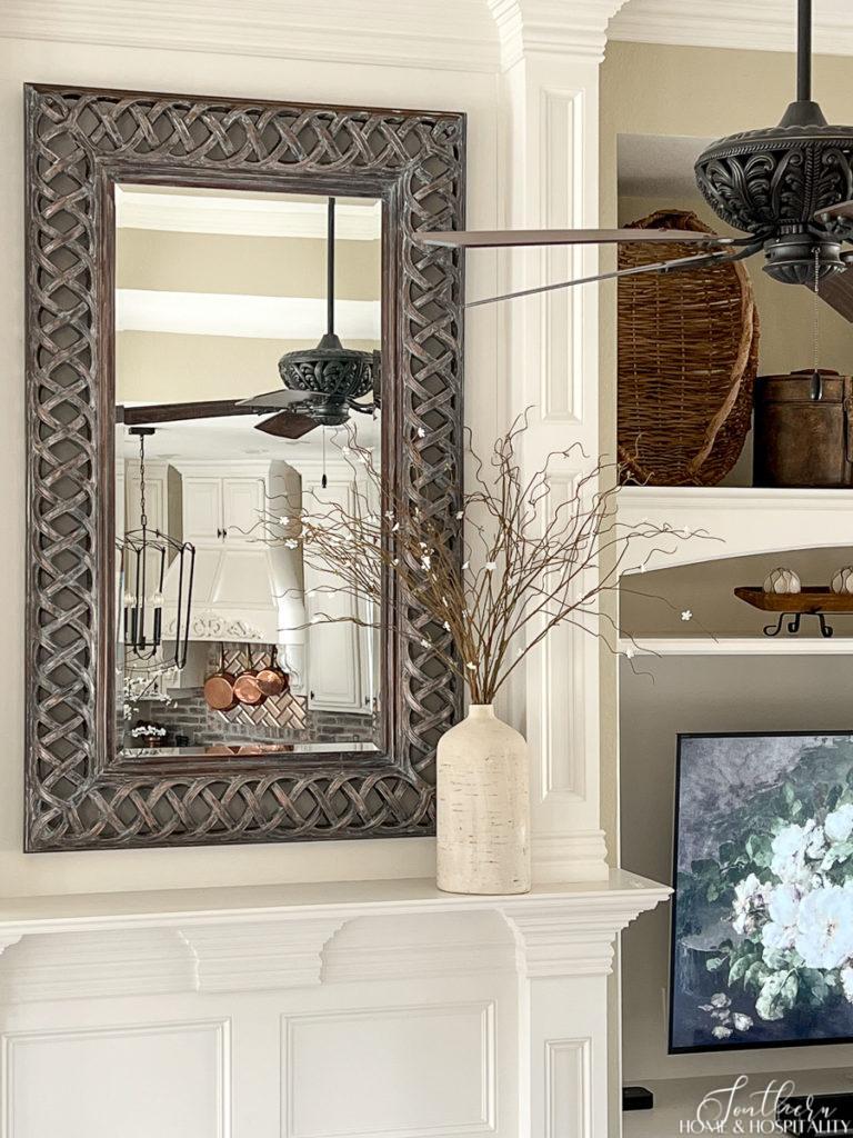 White flowering spring branches in rustic vase on the family room fireplace mantel