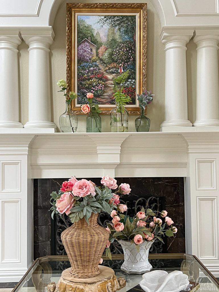 Pink and peach cottage roses in wicker and French pottery in a coffee table vignette and colorful spring flower stems in green and clear glass vases on the mantel