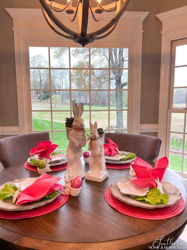 Table set for Easter with bright pink placemats and napkins and white bunnies