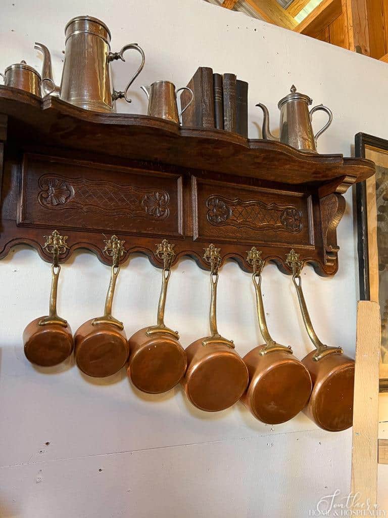 Set of copper pots hanging from antique wall shelf