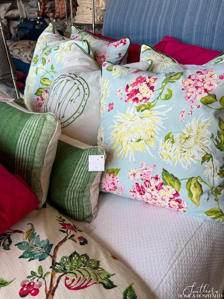 Monogram pillow and colorful floral pillows on a bed