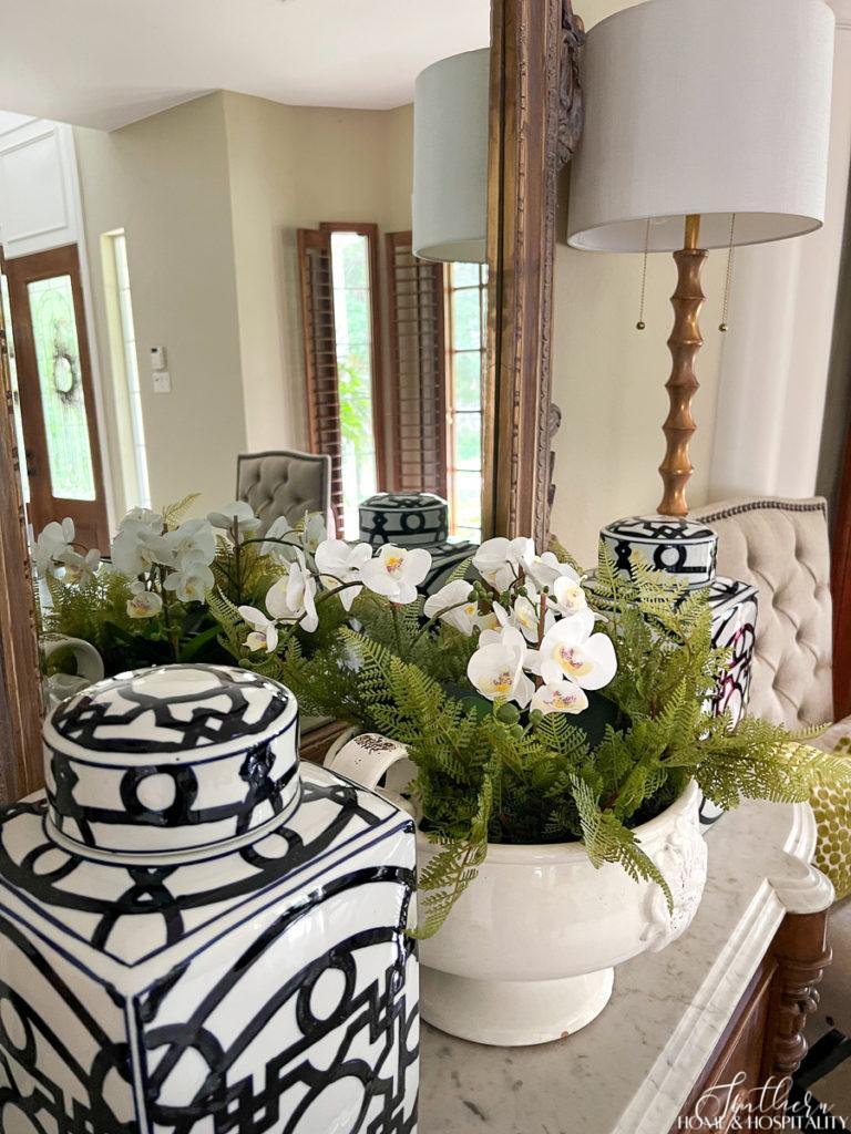 Ferns and orchids in white bowl, blue and white temple jars on dining room sideboard