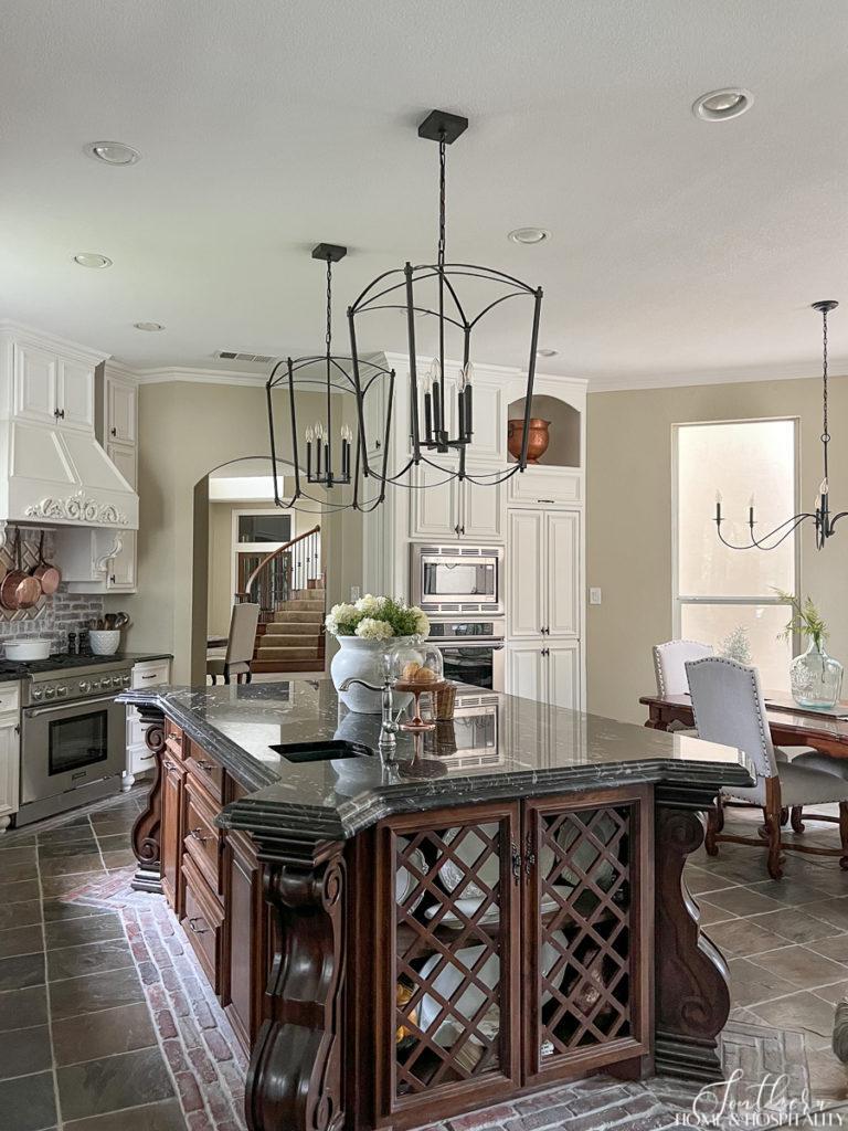 Modern French country kitchen with stained wood furniture island and oversize iron kitchen pendant lights