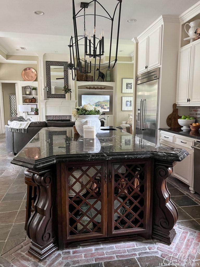 Stained furniture kitchen island with black marble and lattice doors, oversize kitchen pendants