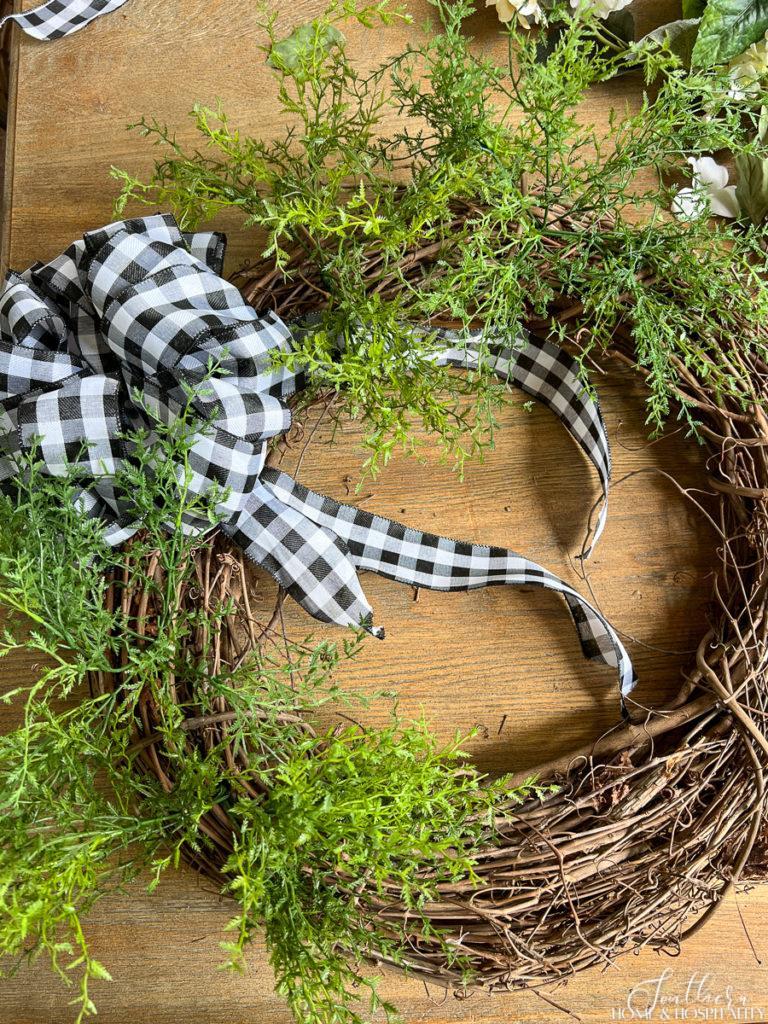 Adding airy greenery to summer wreath