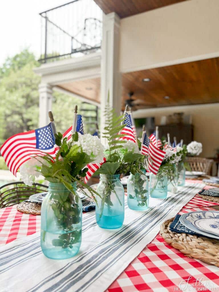 Patriotic table centerpiece idea with mason jars, flags, and flowers