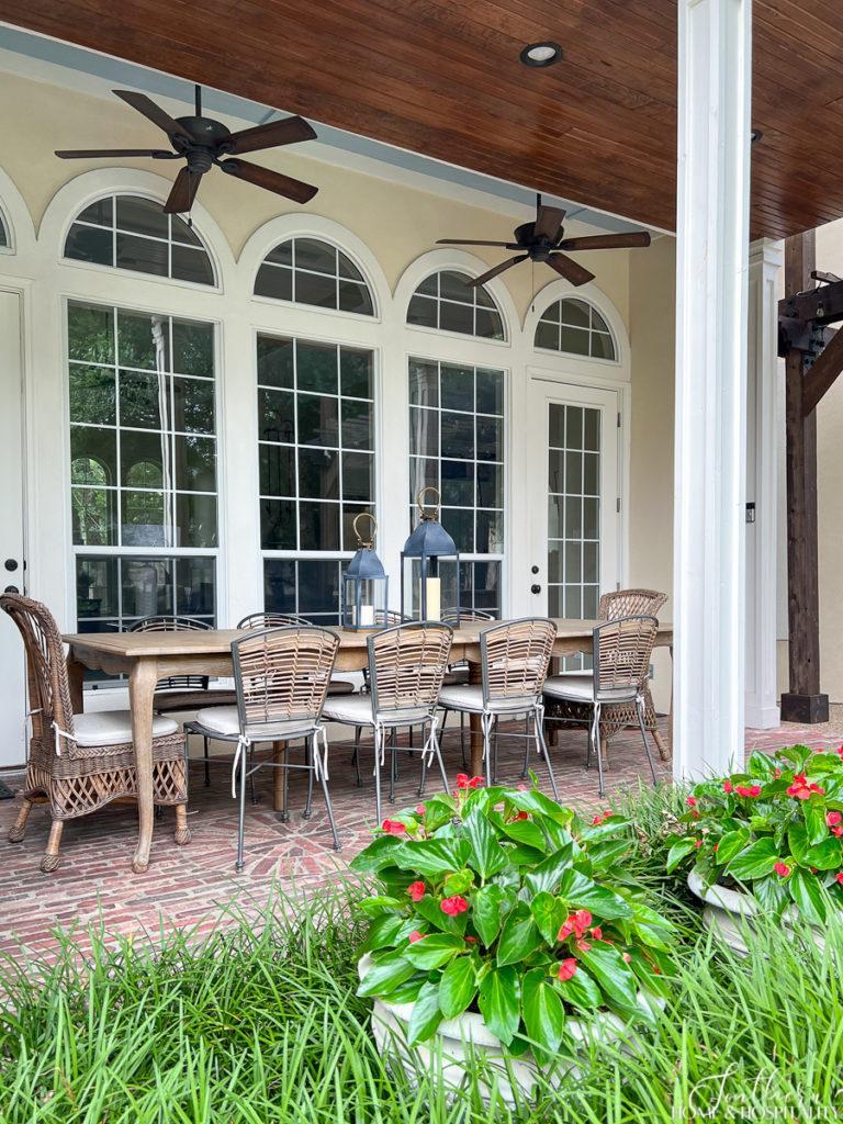 southern back porch with French dining table, rattan chairs, beadboard ceiling, brick floor