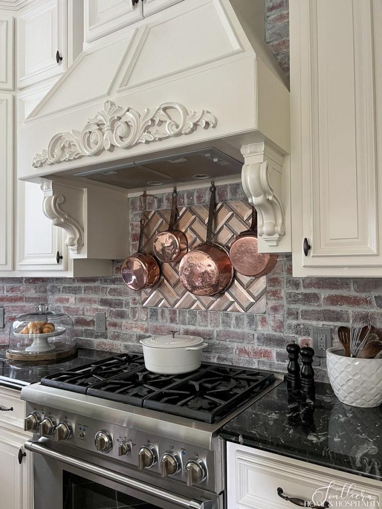 Modern French Country Kitchen with copper pots hanging above cooktop
