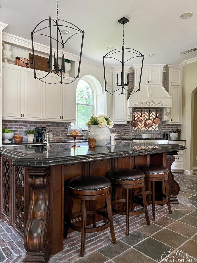 Modern French Country Kitchen with furniture style stained island and white cabinets, oversize kitchen open cage pendants
