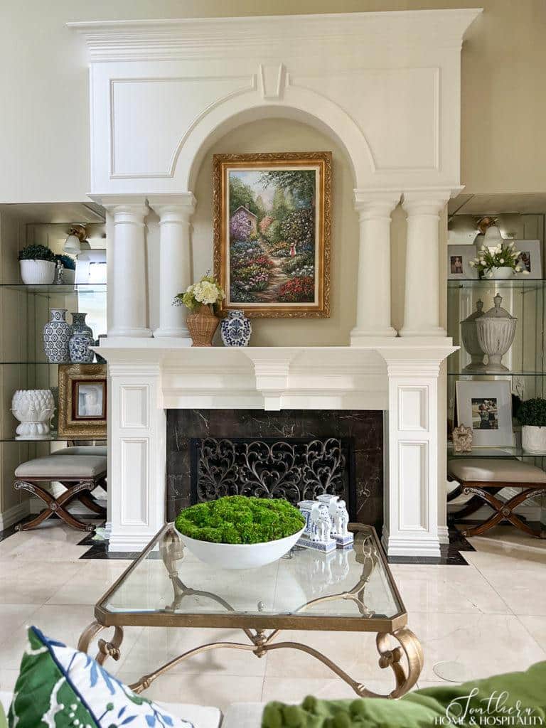 Traditional painted wood fireplace surround with columns and arch, glass shelves with mirror back