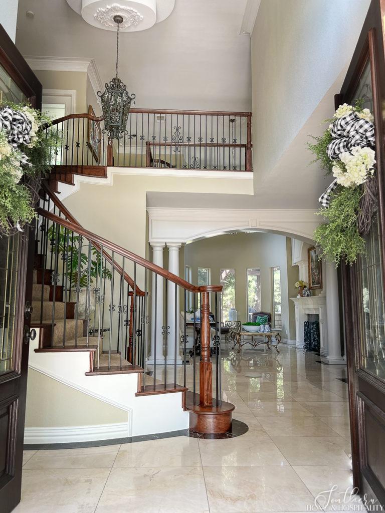 Entry into traditional southern home with curved staircase, marble floors, columns and arches
