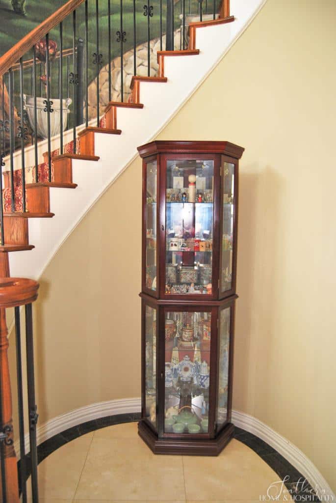 outdated curio full of trinkets under tacky carpet and wall mural