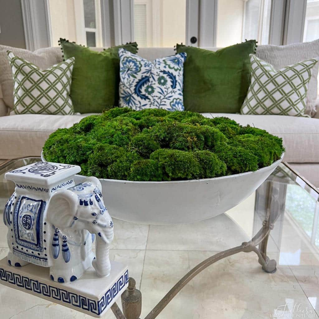 green and blue throw pillows on white sofa, green moss bowl and blue and white porcelain on coffee table
