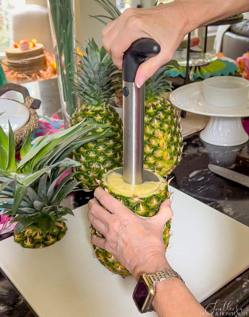 Removing the pineapple from the rind with a pineapple corer and slicer