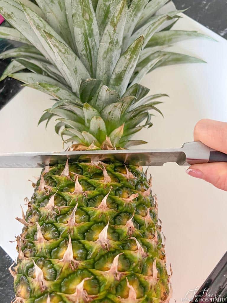 Slicing the crown off of a pineapple