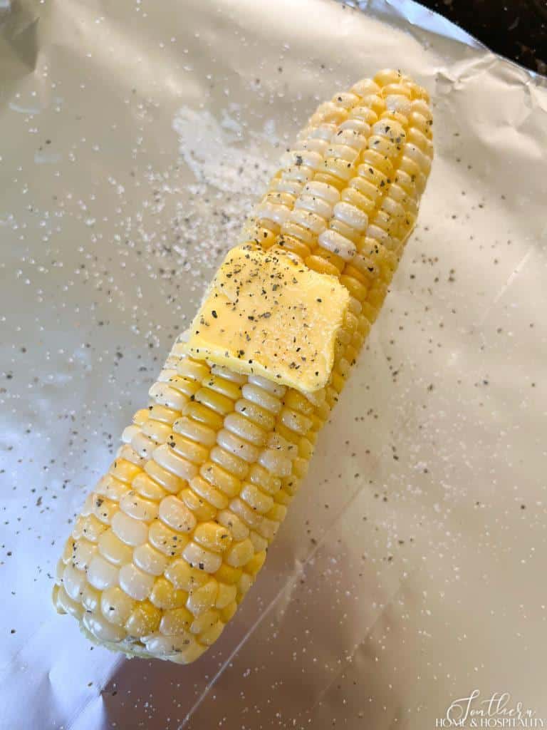 Corn cob prepped for grilling with butter and salt and pepper