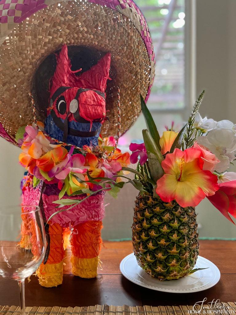 pinata wearing sombrero and pineapple vase of tropical flowers table centerpiece