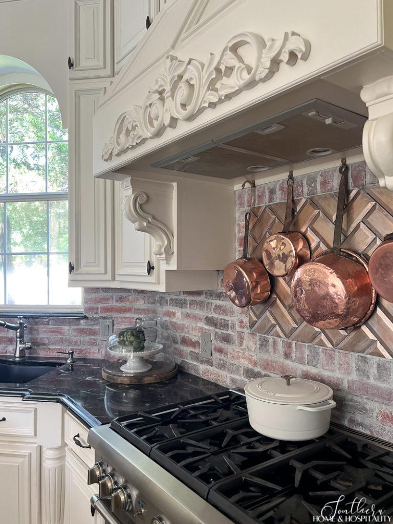 Copper pots over stove in French Country kitchen