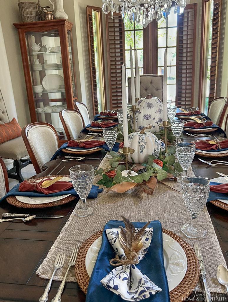 fall place setting with blue and white napkins and feathers