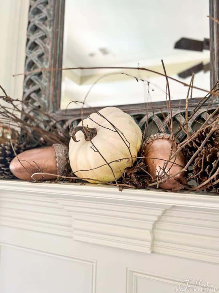 White pumpkin and copper acorns on fireplace mantel