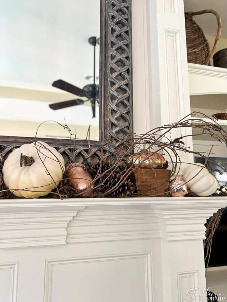 Rustic and elegant fall mantel with grapevine, copper, and white pumpkins