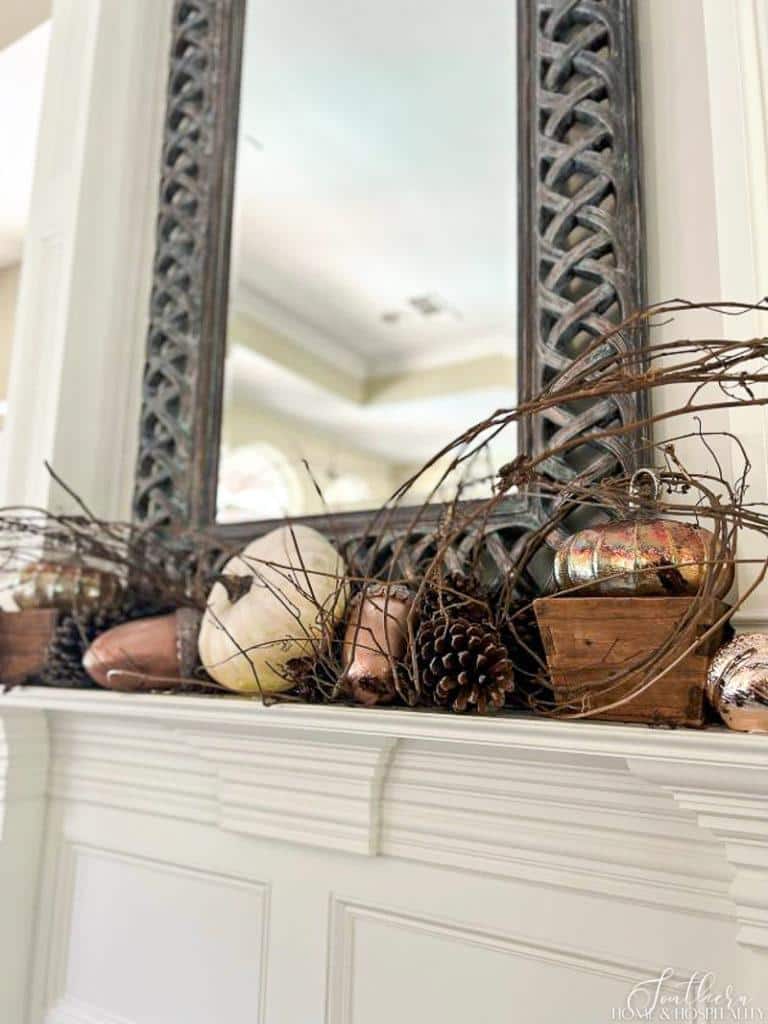 Rustic and elegant fall mantel with grapevine, copper, and white pumpkins