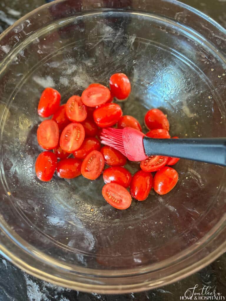 Tossing halved grape tomatoes in oil and salt